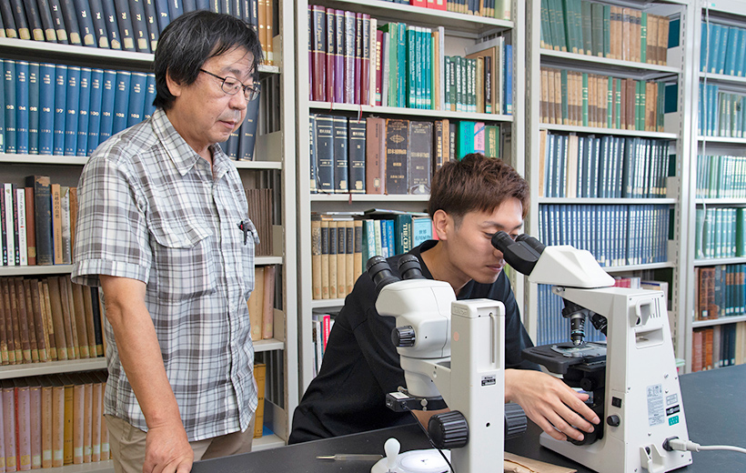 顕微鏡をのぞく学生と山口教授
